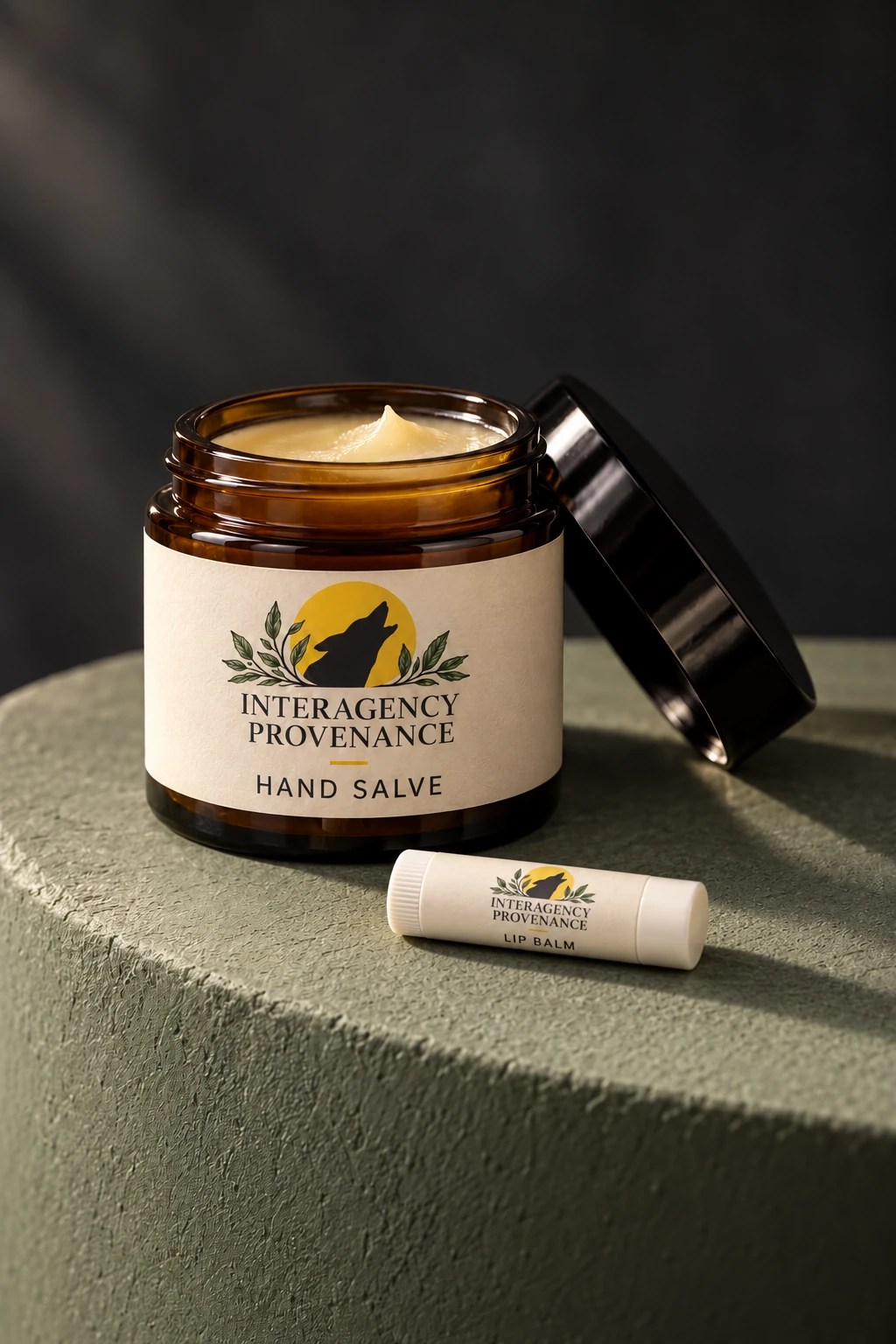 An open amber salve jar and a small lip balm on stone; product concept